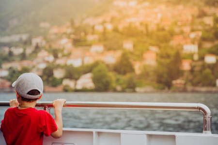 A boy standing on the boat looking to the beautiful view of the lake. a boy dreamの写真素材