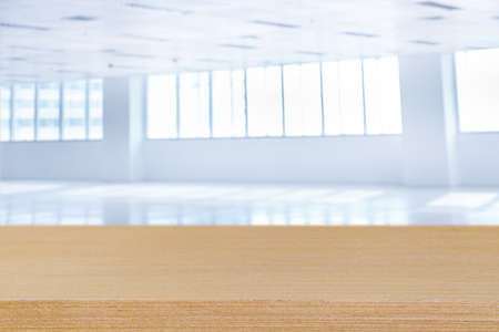 Blank wood table top and Blur of empty modern office space with open clean room to work thought the window and background city.の写真素材