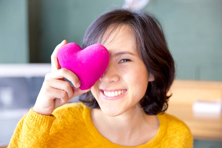 Young cute asian woman with pink heart-shaped pillow and gifts for Valentine's Day.の写真素材