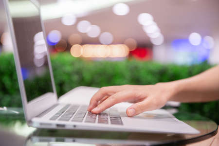 Side view of close up of woman hand typing on the laptop keyboard with bokeh lights.の写真素材