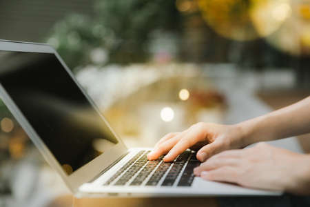Female hands using laptop in modern office or loft near by the window, professional businessman in gray suit working on new project with notebook computer flare light, blurred office building backgroundの写真素材