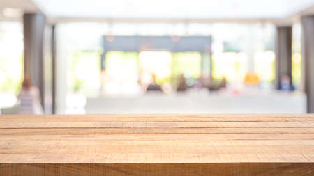 Empty wooden bar counter with Abstract blurred image of people waiting for room registration at reception counter or front desk in the hotel. Warm welcome by receptionist and staff.の写真素材
