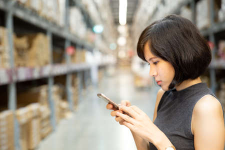 A beautiful woman using smart phone at the warehouse, searching or social networks concept, hipster...