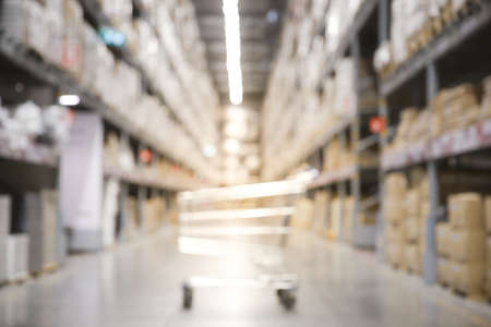 Blurred of shopping cart boxes on rows of shelves in warm light warehouse background.  Using for Mock up template for craft display of your design,Banner for advertise of product.の写真素材