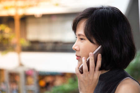Young Asian Girl using smart phone in the shopping mall. Copy space for text and background. ...