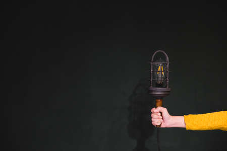 Women hands holding a vintage electric lamp in a metal grid lampshade, a lamp in a cage. Lock idea in cage concept.の写真素材