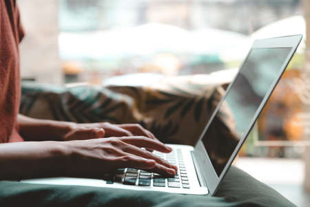 Close-up of female hands using laptop at cafe, woman's hands typing on laptop keyboard in interior. side view of businesswoman using computer in vintage tone.の写真素材