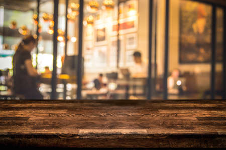 Real dark Wood table top with defocused background of restaurant, bar or cafeteria background empty or copy space for text or product presentation.の写真素材
