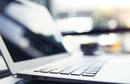 Selective focus of Side view laptop is on the work table in a conner office with morning light. Business background concept.の写真素材