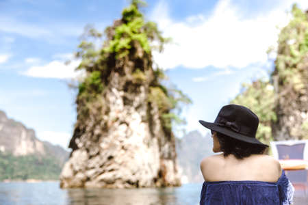 Back side of a woman sitting on long tail boat and enjoying the view of ocean and islands.の写真素材