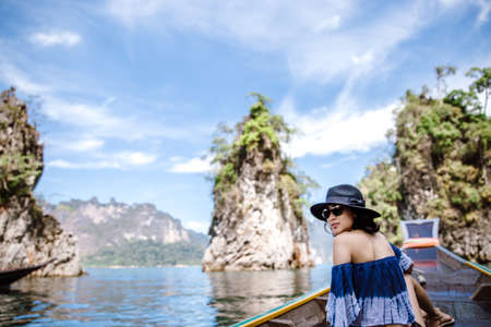 Back side of a woman sitting on long tail boat and enjoying the view of ocean and islands.の写真素材