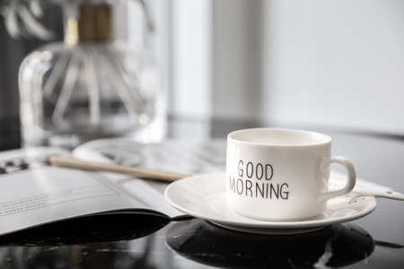 White coffee mug with bouquet of flowers lily of the valley and notes 'good morning' on black modern marble table. Beautiful sunshine morning refreshment.の写真素材