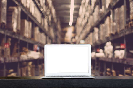 Mock up of modern computer or laptop with blank screen on table with Blurred boxes on rows of...