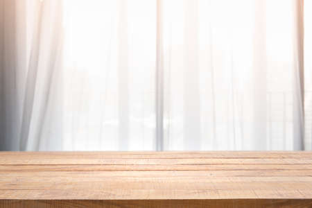 Empty of wood table with Blur of curtain window and pillow in livingroom with sunlight. For montage...