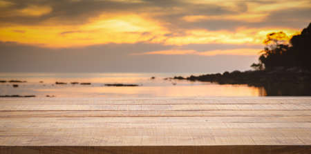 Empty wooden bar counter with blurred sunset beach background. Using for Mock up template for craft display of your design,Banner for advertise of product.の写真素材