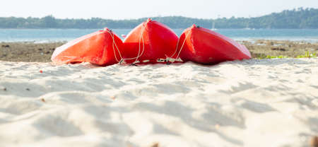 A few cannoe stand on a sandy beach.  Red kayaks on the tropical beach, Active rest, sport. Summer conceptの写真素材