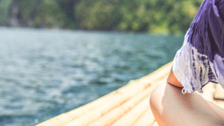 A woman on the bamboo rafting on the lake or river. Summer activity and holiday vacation concept. Copy space for summer text.の写真素材