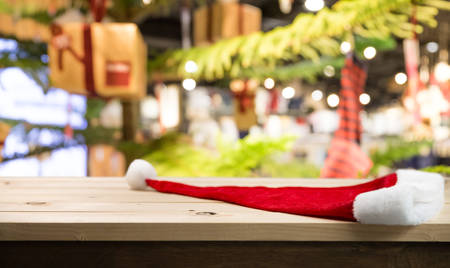 Christmas holiday background with empty wooden table top and christmas hat over. Blur abstract...