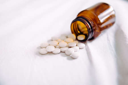 Pills spilling out of pill bottle on white, copy space. Medicine concept
