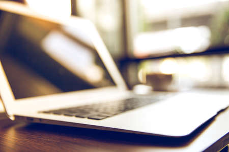 Selective focus of Side view laptop is on the work table in a conner office with morning light.