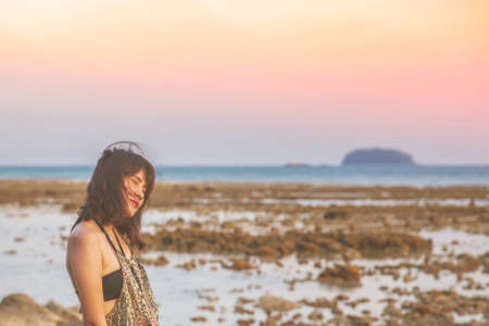 Young woman in casual style fashion Standing on the beach. Relaxing and enjoy holiday at tropical paradise beach. Girl in summer vacation. Summer vibes.の写真素材