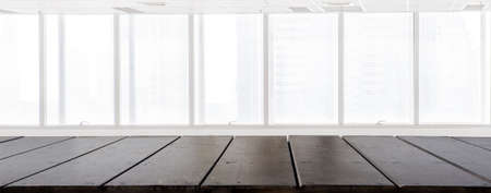 Empty wood table top with Blur inside office building with window background, interior and business background. Using for Mock up template for craft display of your design,Banner for advertise of product.の写真素材