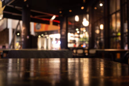 Empty real wood table top with light reflection on scene at restaurant, pub or bar at night. Blurred background for product display or montage your products with several concept idea and any occasion.の写真素材