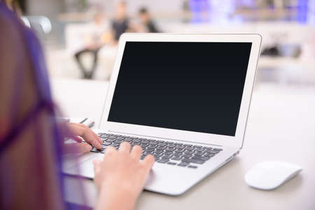 Isolated mockup image of laptop and female hand typing to blank screen laptop. Freelancer or student working on new project. Business concept.の写真素材