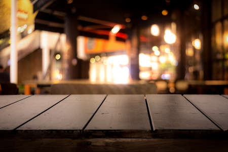 Empty real wood table top with light reflection on scene at restaurant, pub or bar at night. Blurred background for product display or montage your products with several concept idea and any occasion.の写真素材