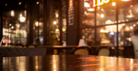 Empty real wood table top with light reflection on scene at restaurant, pub or bar at night. Blurred background for product display or montage your products with several concept idea and any occasion.の写真素材