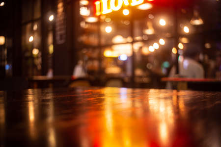 Empty real wood table top with light reflection on scene at restaurant, pub or bar at night. Blurred background for product display or montage your products with several concept idea and any occasion.の写真素材