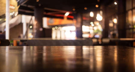 Empty real wood table top with light reflection on scene at restaurant, pub or bar at night. Blurred background for product display or montage your products with several concept idea and any occasion.の写真素材