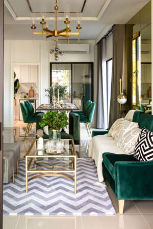 Modern scandinavian living room interior with dark green sofa, design commode, leaf in vase, cozy pillow, and elegant accessories. Template. Stylish home decor.の写真素材