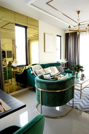 Modern scandinavian living room interior with dark green sofa, design commode, leaf in vase, cozy pillow, and elegant accessories. Template. Stylish home decor.の写真素材