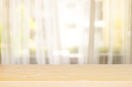 Wood table top with Blur of curtain window from green garden view in morning background. For montage product display or design key visual layout.の写真素材