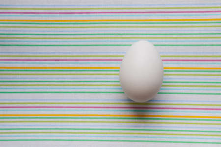 chicken egg on a colored striped background. concept of healthy organic farming eco food, copy space for textの写真素材