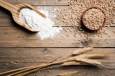 Ear grains, flour and wholegrains on wood tableの写真素材
