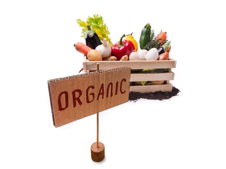 Organic vegetables in wooden rustic box and topsoil with cardboard square tag. Price tag, gift tag, sale tag,  label isolated on white backgroundの写真素材