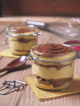 Italian traditional classic Tiramisu dessert on a opened glass jar. rustic compositionの写真素材