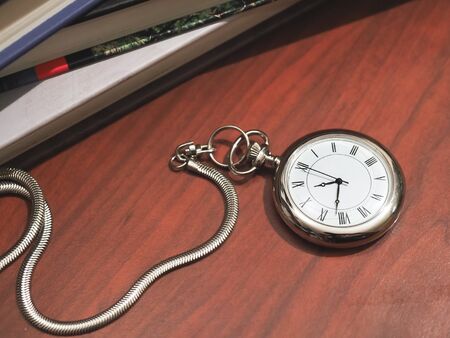 caucasic man holding a pocket clock on classic desk backgroundの写真素材