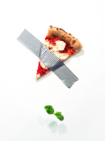 SPizza slice taped on the wall with duct tape reminding the composition of Maurizio Cattelan