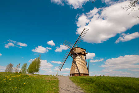 Old ancient historical windmill in countryside village. Pleasant sunny weather, blue sky, white...