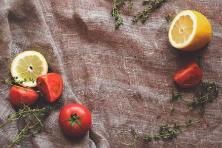 Bloody Mary Cocktail ingredient. Red tomatoes yellow lemon and spice herbs on brown rustic raw sackcloth fabric photo. A4 A5 international paper slide poster card with free blank copy space for text.の写真素材