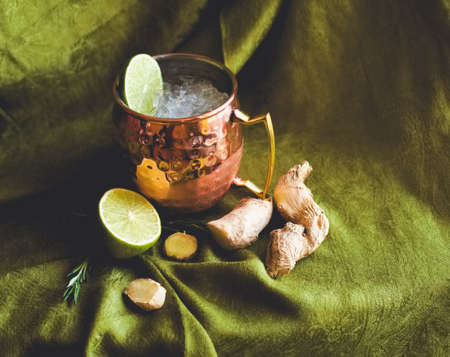 Home made cocktails ingredients lemon ginger ice and classic Moscow mule in copper mug on green fabric. For social media network blogs drink recipe posts, bar restaurant ads.の写真素材