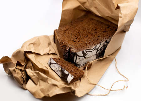 Home cooked healthy wholegrain rye dark traditional Russian bread loaf in rustic craft paper on white battleground. Farmers market bakery, healthy food shop ads or website design, organic eating blog.の写真素材