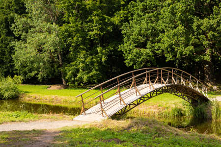 Dukora Maentak Museum Minsk region. A bridge in a park. Sunny good weather, green trees and blue sky