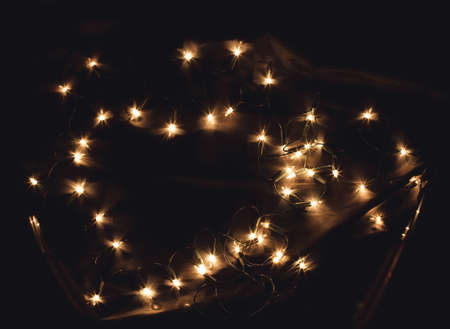 Heart shaped New Year Christmas Holiday celebration light garland on black background. A frame with free blank copy space for text. Good for romantic Valentines day cards, invitations or postersの写真素材