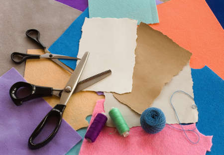 Variety of felt fabric pieces of different colors and scissors, piece of paper with copy space for text. A colorful pattern background for hand-made hobby shop website decor, social network designの写真素材