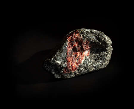 Raw garnet almandine stone crystal inside granite rock isolated on black. Found in Kem, Karelia,...