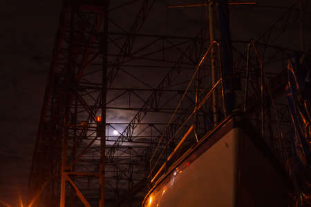 Klaipeda, Lithuania - 11 28 2020: boats at night. Dramatic dark photo, metallic dock construction...